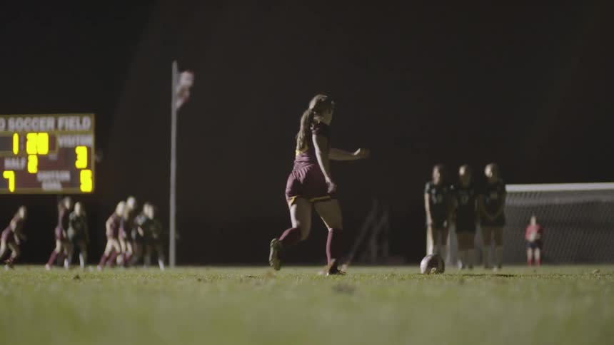 A soccer player runs and kicks a soccer ball
