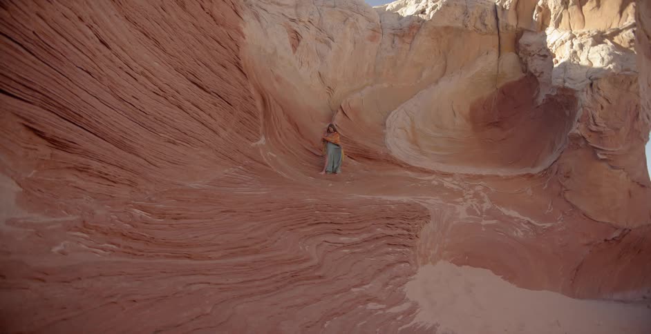 A woman walks on red rock in the desert