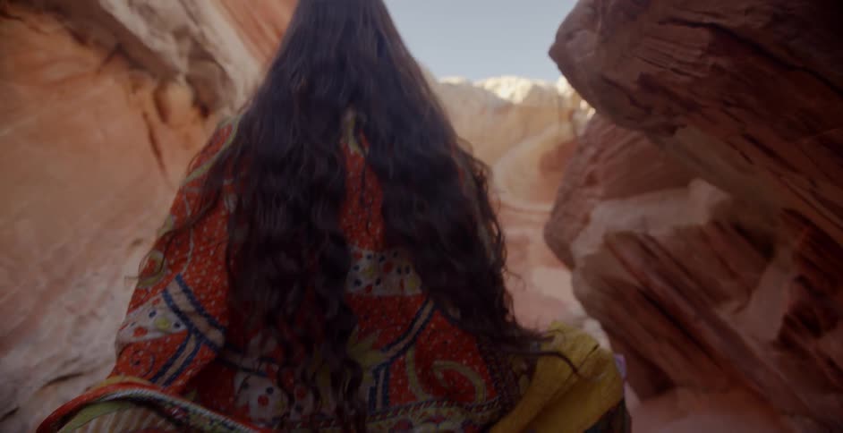 A woman walks by red rock formations in the desert