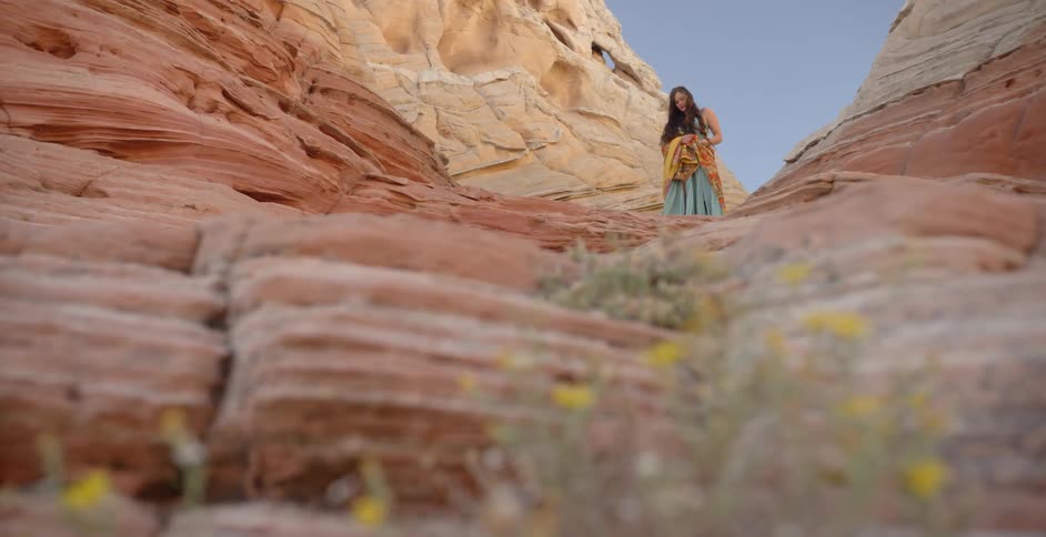 A woman stands on red rock formations in the desert