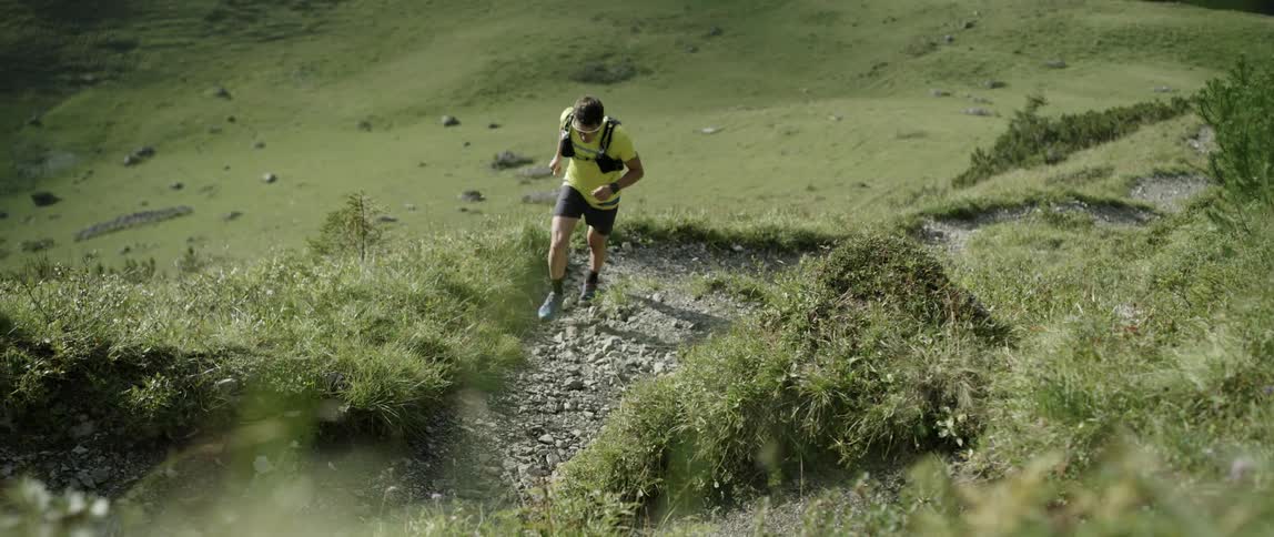 Man running up trail on side of hill during the day