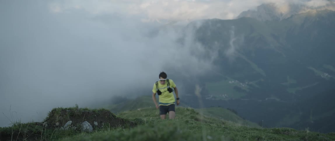 A man is jogging up a steep hill in a mountain range