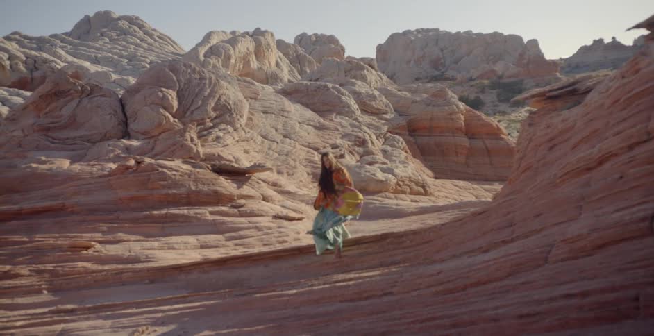 Woman walks over rocky hills in a desert