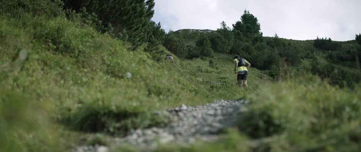 A man is running on the green hill on a cloudy day
