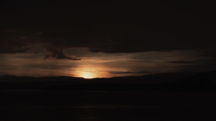The sun slowly sets over the mountains ahead