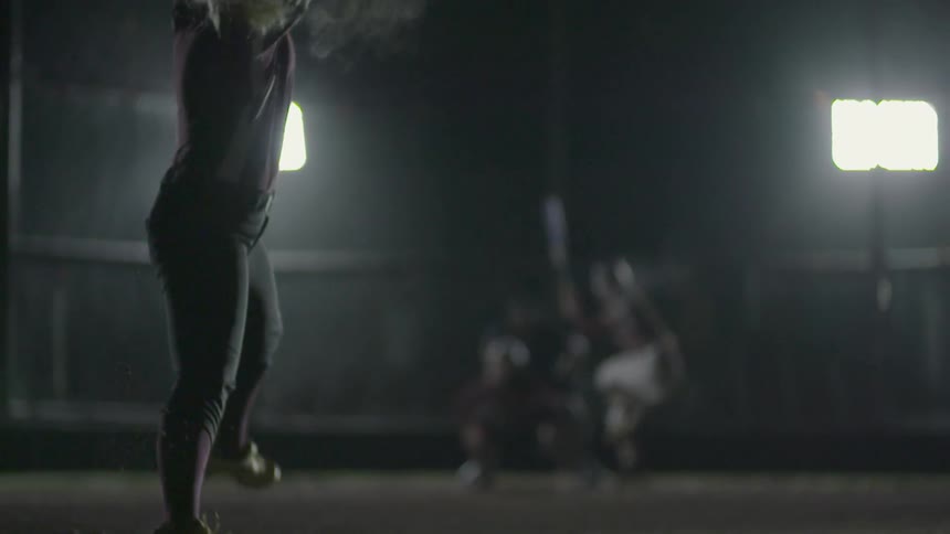 A pitcher underhand throws a softball to a batter