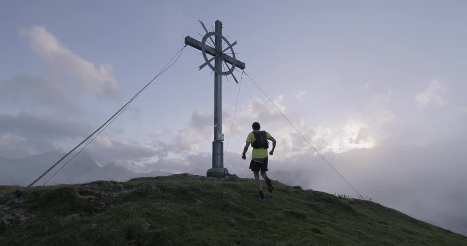 A man runs uphill towards a large cross