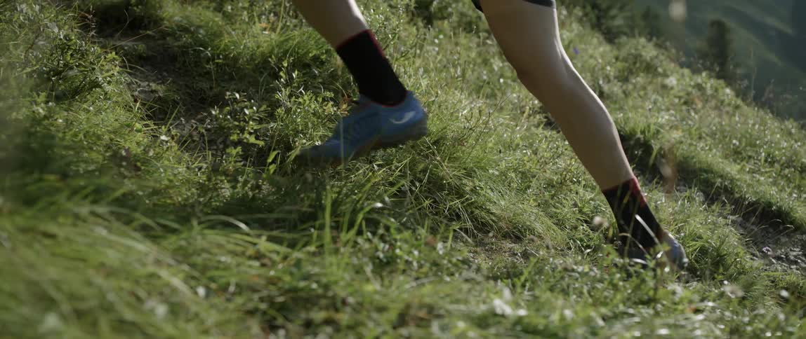 Person's legs jogging up a grassy hill