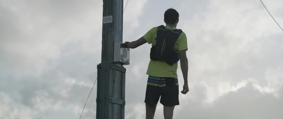 A man stops to rest near an electrical tower as he jogs on a hill