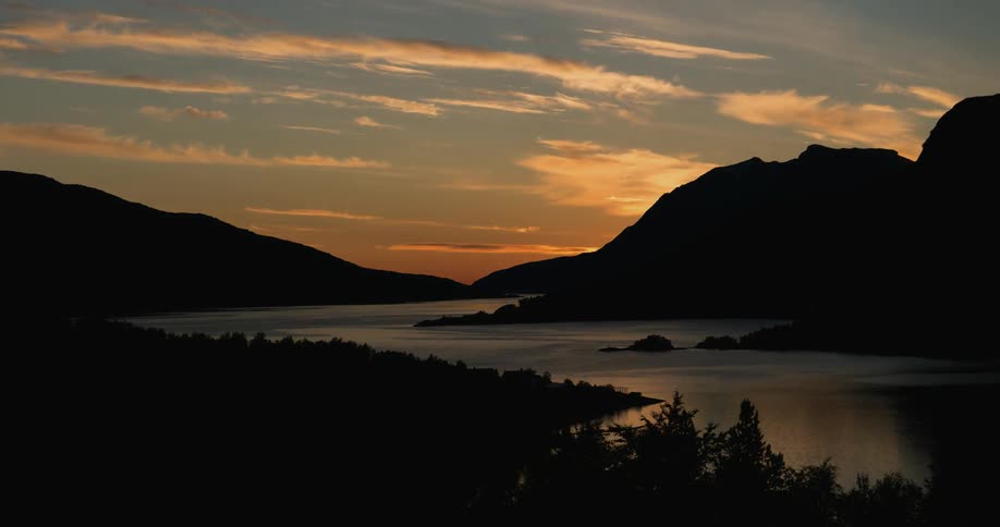 A fast moving sunset over some water and mountains