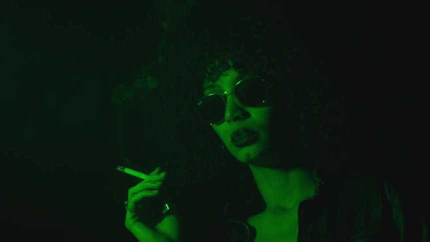 A woman smokes in a dark room