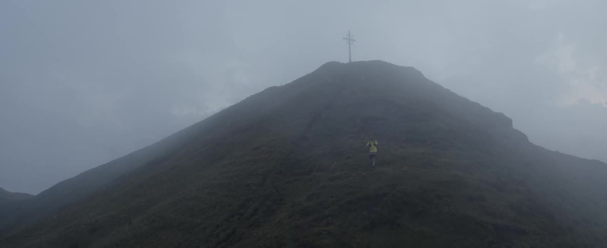 The hillside is covered with heavy fog as a man descends