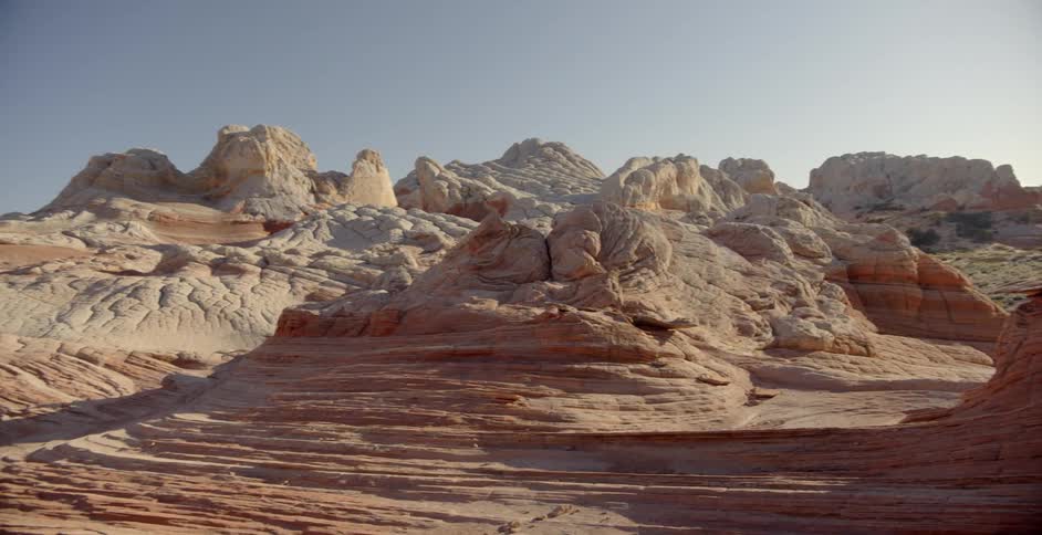 Red rock formations stand in a desert on a sunny day