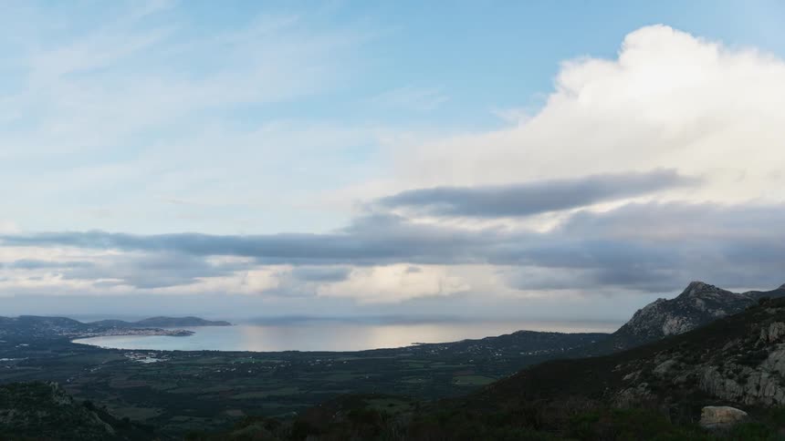 Clouds pass by above the seashore and a mountain