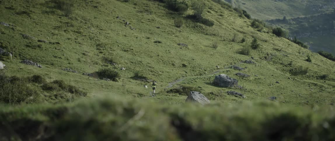 A man jogs up a mountain trail on a sunny day