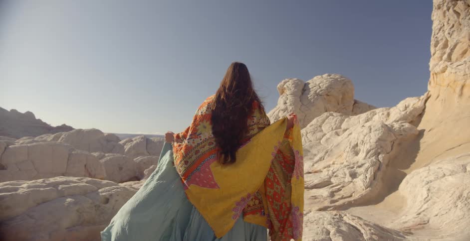 A woman wearing flowy clothing is walking in a canyon area