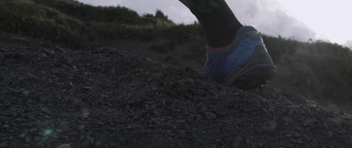 Person jogs up a grassy dirt hill