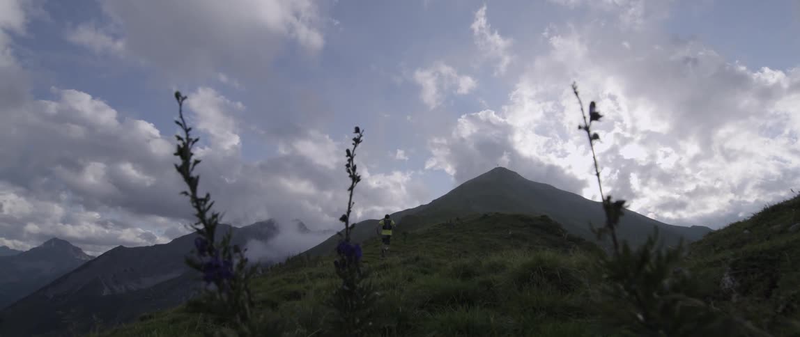 A man jogging up a large hill by a mountain
