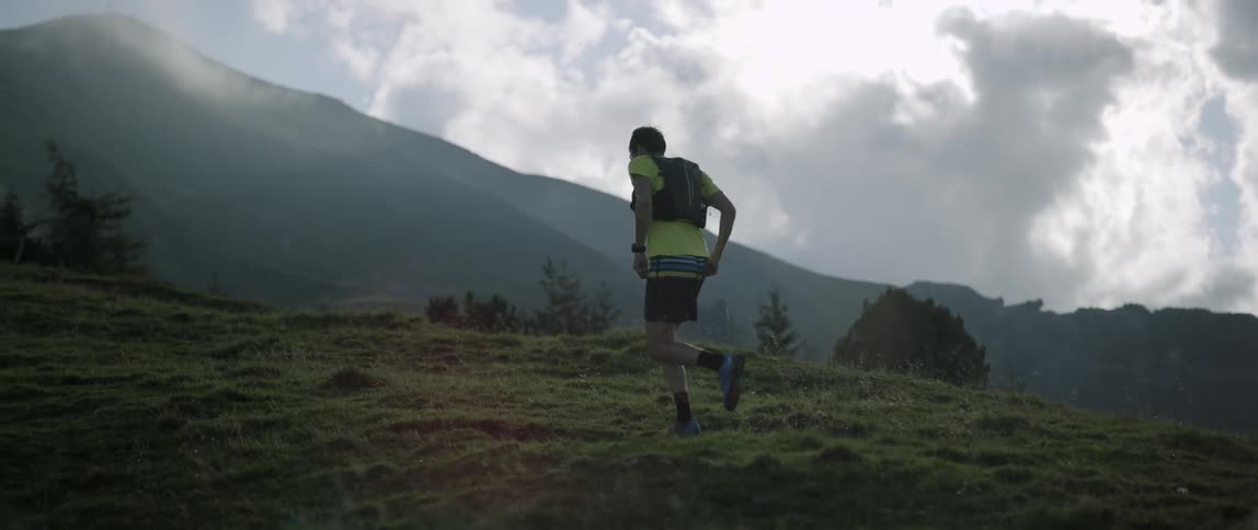 A man runs up a mountainside on a cloudy day
