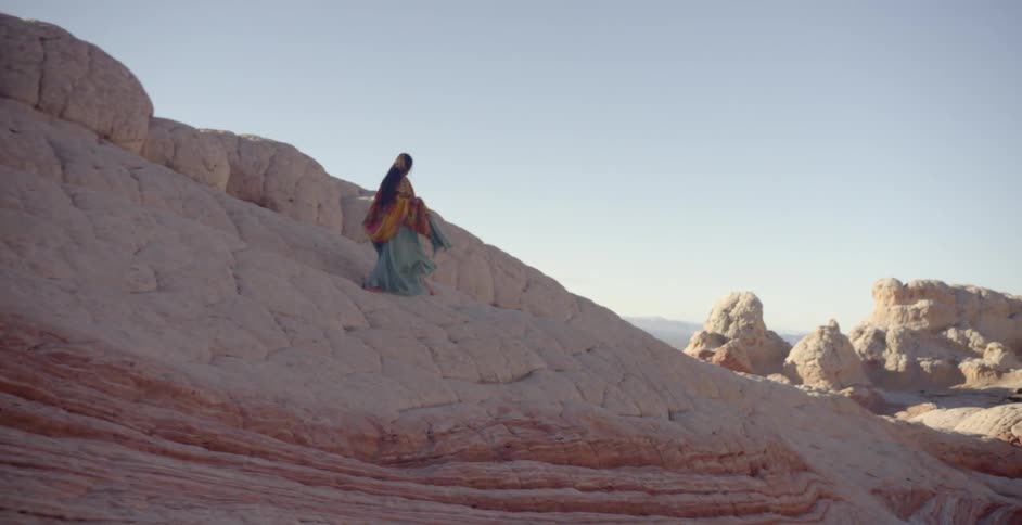 A woman is walking on the rocks on a sunny day