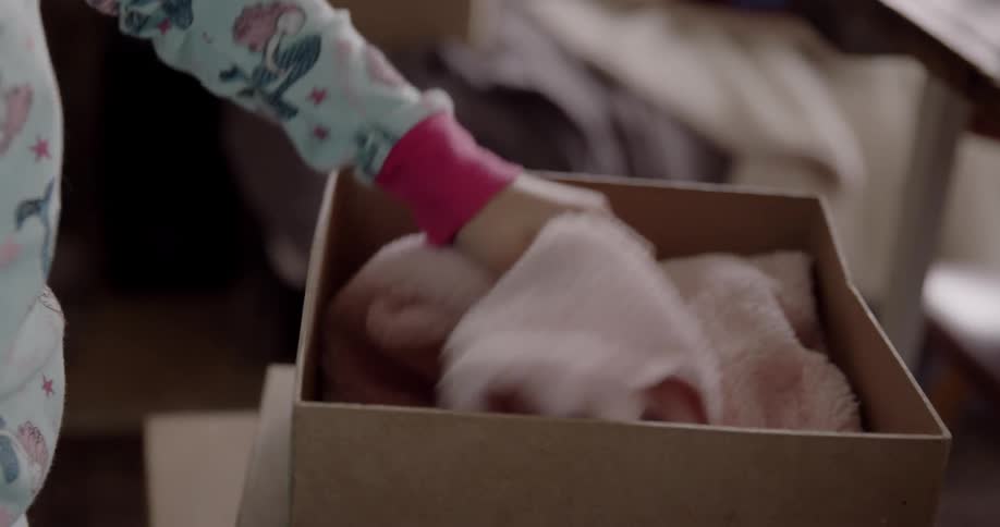 A young child opens a box and grabs a sweater out of it