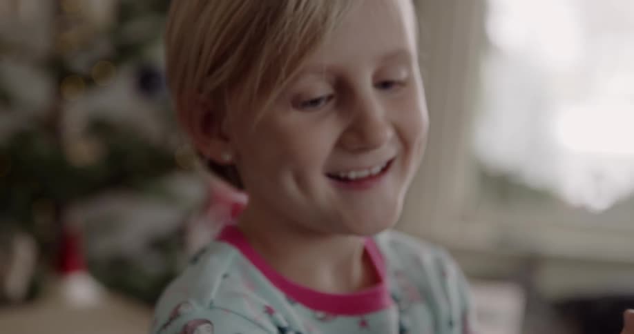 A young girl in a living room is smiling as she holds something