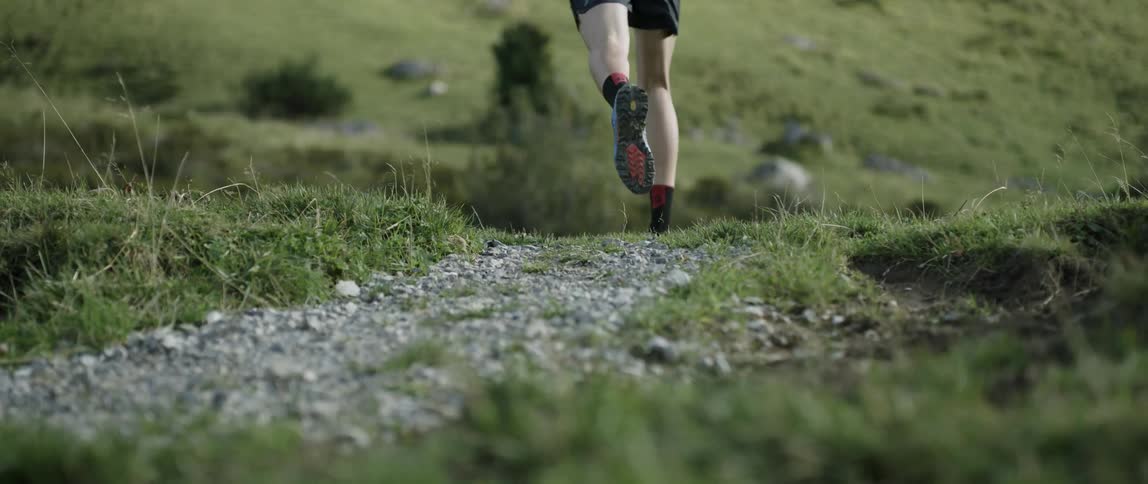 A man runs down a trail over a hill