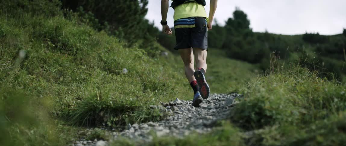 There is a small rock trail that a man is running on