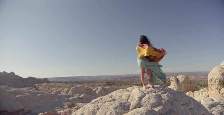 A woman is standing on a rock on a windy day