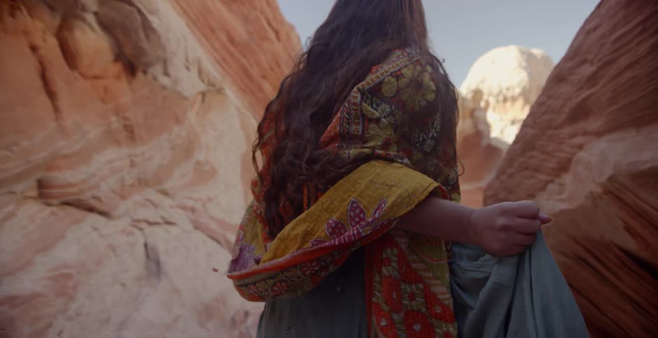 A woman walks past some canyon walls then breaks into a run