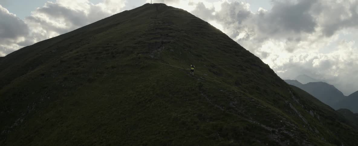 A person is running up a small trail on a tall mountain