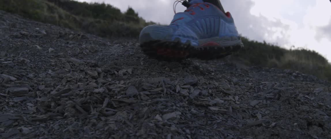 A man runs up a mountainside on a cloudy day