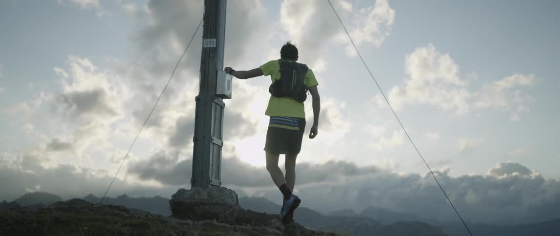 A man runs up a hill towards a steel post