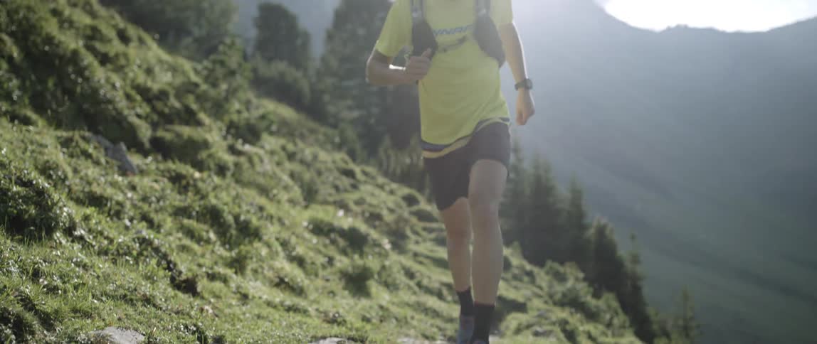Man jogs up a grassy mountain