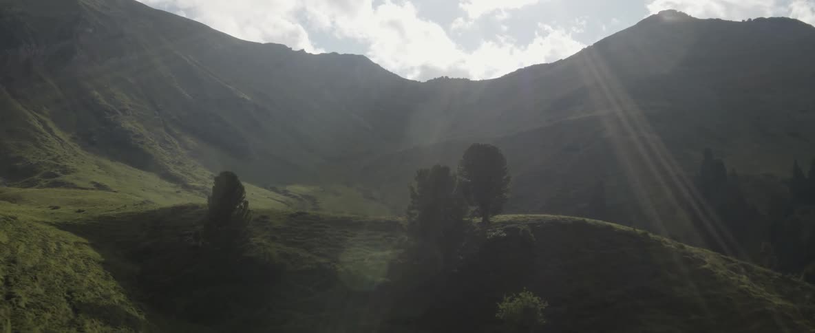 The sun casts rays of light on a mountain valley