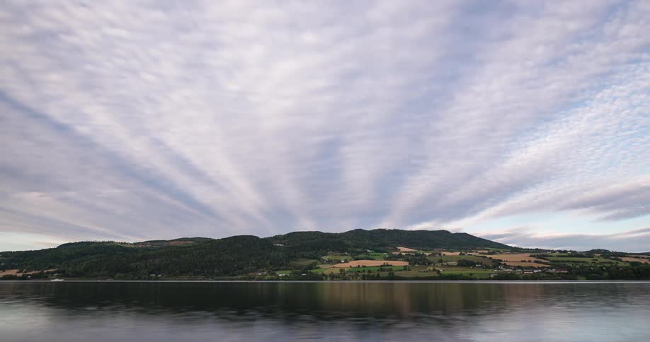 Water flows through a lake as streaming clouds pass above