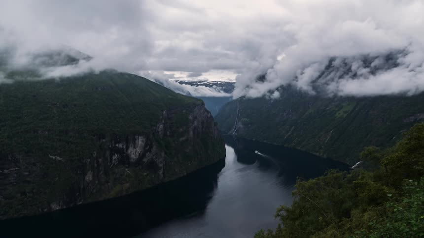 A boat passes through a fjord between two mountains