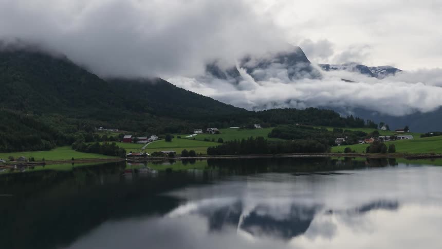 The green mountains are covered with clouds