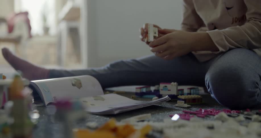 Child looks at a book to figure out how to build something out of blocks