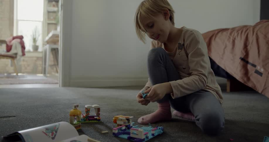 A child is building legos on the floor