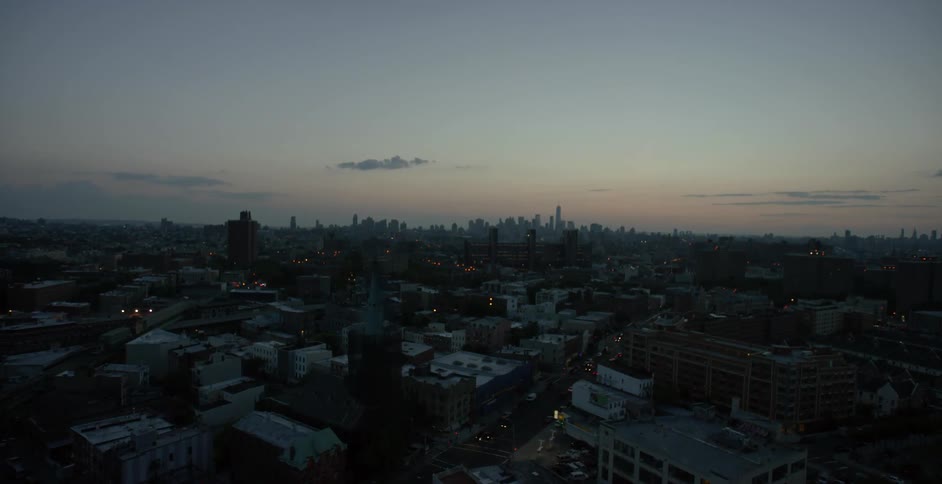A city sits under a mostly cloudless sky in the dark at dusk