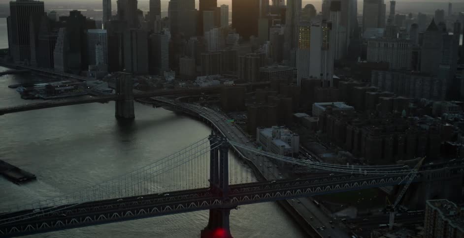 Aerial view of a bridge and some roads around a very large city at dusk