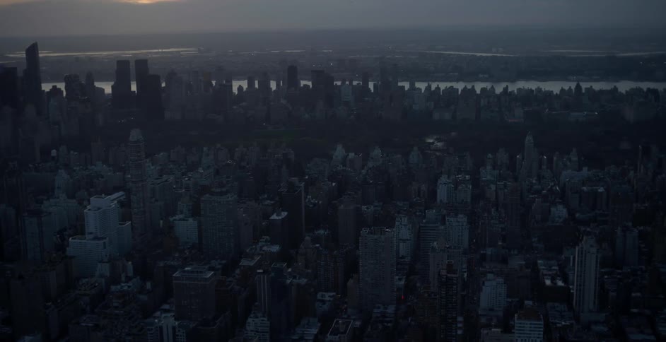 An aerial view of an urban area and body of water at dusk