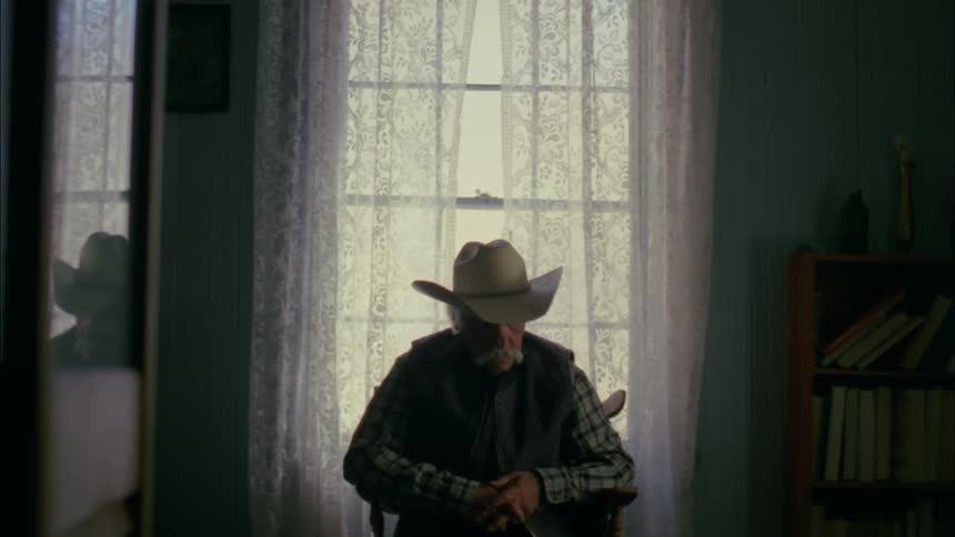 Older man sitting still in chair next to window