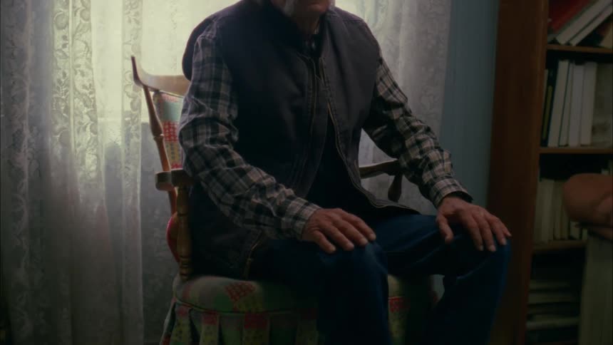 Man sitting in a chair next to window in a house