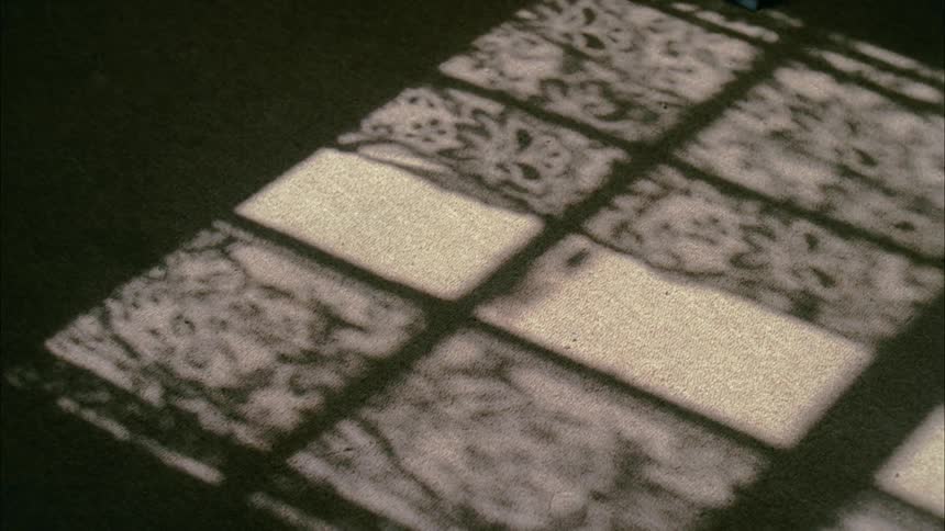 Shadow on the ground of lace curtains hanging in a window