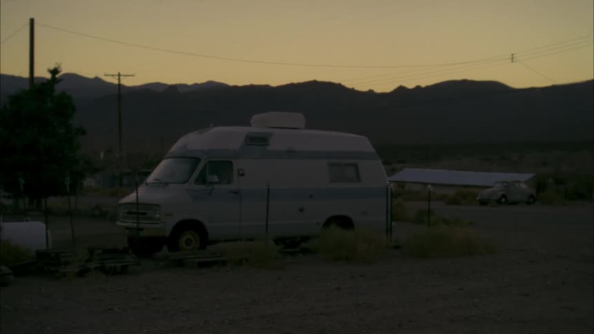 A camper van is parked beside a fence