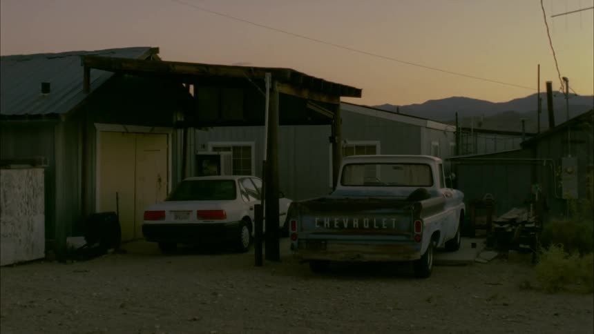 Car and truck parked next to some buildings at dusk