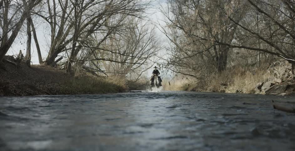 A cowboy rides a horse in a river