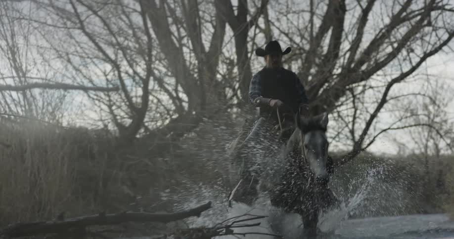 A cowboy rides a horse in a river